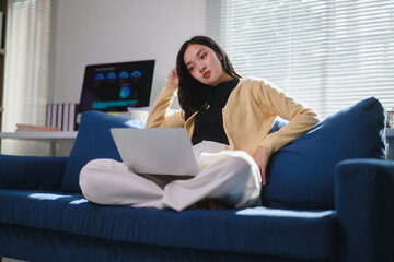 Young Professional Woman Relaxing with Laptop on Sofa