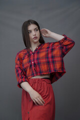 Confident Young Woman in Red Plaid Shirt and Long Buttoned Skirt Posing Indoors
