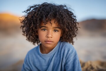 A young boy with curly hair gazes thoughtfully at the camera in a serene outdoor environment highlighting his innocence and connection to nature showcasing the beauty of childhood