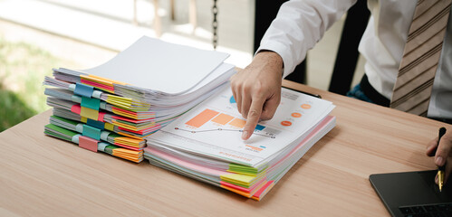 Portrait of businessman working with stack of documents to search for information and check...