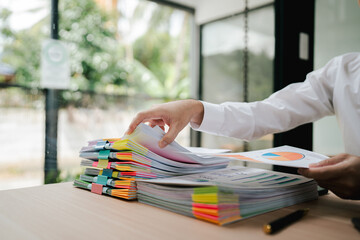 Portrait of businessman working with stack of documents to search for information and check...