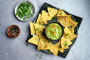 Crispy tortilla chips arranged in a bowl beside a guacamole dip, a classic Mexican appetizer.