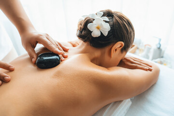 Hot stone massage at spa salon in luxury resort with day light serenity ambient, blissful woman...