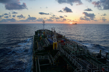 A merchant ship underway at sea in the morning under dramatic sky