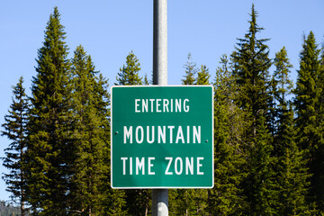 Rural sign with message in white text on green Entering Mountain Time Zone