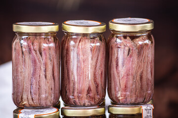 A close-up of beautifully preserved anchovies in elegant glass jars with golden lids. This image showcases the art of traditional food preservation, highlighting the quality and craftsmanship behind t