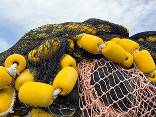 High pile of industrial fishing nets with yellow floats on rope