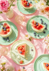 Watermelon dessert slices on pastel plates, adorned with berries, on a pink tablecloth, with flowers