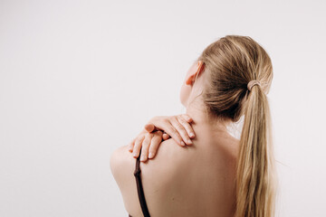 Woman with long hair is holding her shoulder in discomfort, showcasing the physical sensation of...