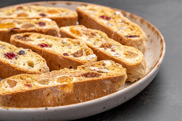 Italian Almond Biscotti biscuits in a rustic home made pottery bowl. Studded with almonds and cranberries, these twice-baked treats are aromatic and inviting. Ideal.