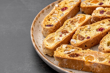 Italian Almond Biscotti biscuits in a rustic home made pottery bowl. Studded with almonds and cranberries, these twice-baked treats are aromatic and inviting. Ideal.