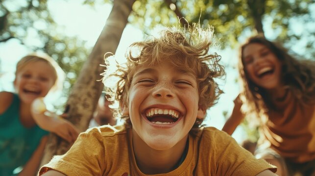 A close-up of a delighted boy laughing amidst friends, capturing the essence of joy and friendship in a vibrant outdoor setting filled with sunlight and greenery.