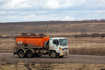 A tanker truck drives along a highway outside the city