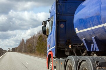A tanker truck drives along a highway outside the city