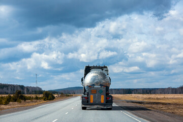 A tanker truck drives along a highway outside the city