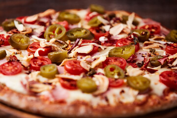 Pizza with ham, cherry tomatoes and mozzarella cheese. Wooden background. Soft focus. Close up.	