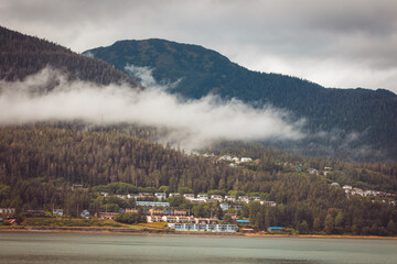 Cruise ship at a port in Juneau, Alaska with snow capped mountain and low lying fog in the background