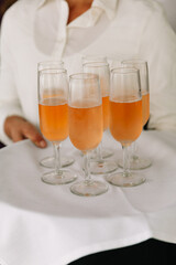 Waitstaff serves sparkling beverages on a tray at an elegant event setting in the afternoon