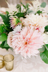 Elegant floral arrangement with pink dahlias and greenery at a wedding reception in the afternoon