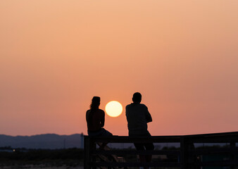Silueta de una pareja al atardecer con el sol entre ambos