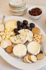 Elegant cheese platter with assorted cheeses, crackers, fruits, and nuts arranged for a gathering in a cozy setting