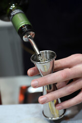 barman experto en coctel elaborando un coctel con el medidor dosificador de licor con sus manos 