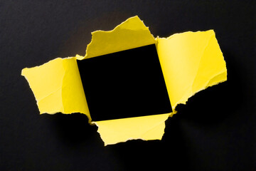 A vibrant yellow tear reveals a black square, a stark contrast against a dark background