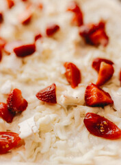 Unique pizza close-up featuring melted cheese, sliced strawberries, and cherry tomatoes. Creative...