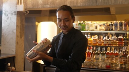 Closeup Asian hand bartender shaking mixed cocktail at luxurious counter preparation for making...