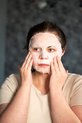 Woman doing skincare ritual with hydrating face mask. Evening beauty routine to soothe facial skin after hard day. Self care concept.