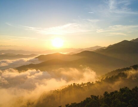A view of mountains with clouds and a bright sun shining in the sky during the golden hour light - Powered by Adobe