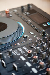 Close-up of DJ audio controller with knobs and faders, modern electronic music equipment used for...
