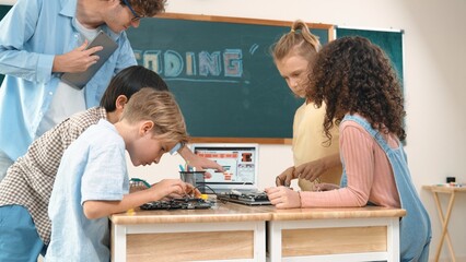 Group of diverse student working together on main board with laptop screen display engineering...