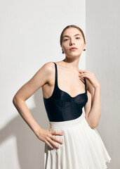 A stylish woman in tennis clothes poses against a light background in the sunlight