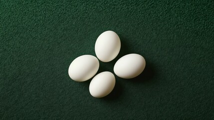 Top view of four white eggs on a dark green background