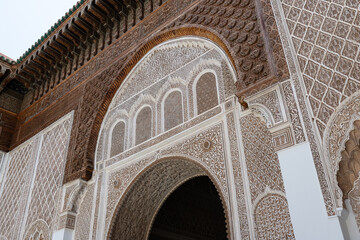 Intricate carvings and geometric patterns adorn the archway and facade of ben youssef medersa, a historical islamic college in marrakech, morocco, showcasing stunning islamic architecture