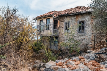 Old, abandoned stone house on the rocky hills of Alanya Castle, Turkey, surrounded by overgrown bushes and trees. A forgotten piece of history blending with nature