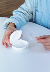 Manos de chica con estuche y retenedores dentales invisalign de ortodoncia digital o 3d.   © Will Labrador