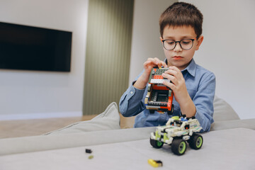 Boy assembling toy car at home using building blocks