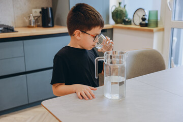 Little Boy Drinking Water From Glass in Kitchen
