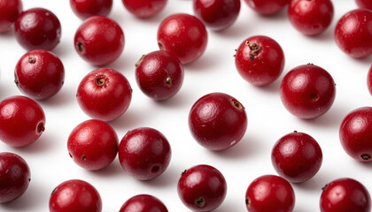 Red cranberries lie scattered across a white surface. These fresh berries await use in recipes, adding a vibrant color and tart flavor to dishes, especially during the holiday period