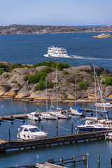 Archipelago ferry leaving harbour with ships at Saltholmen peninsula on the shore of Alvsborgsfjorden, Alvsborg district, Gothenburg, Sweden, sunny day
