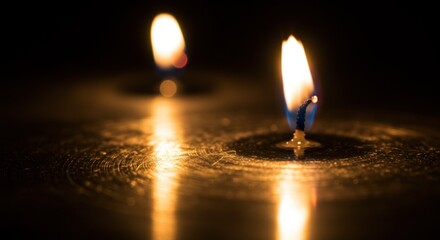 Burning candles reflecting on dark surface