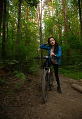 Beauty smiling woman biking on bicycle on spring trees green forest background, looking happy....