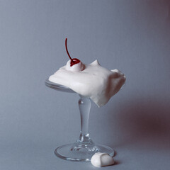 Whipped cream overflowing a glass stem with a cherry on top