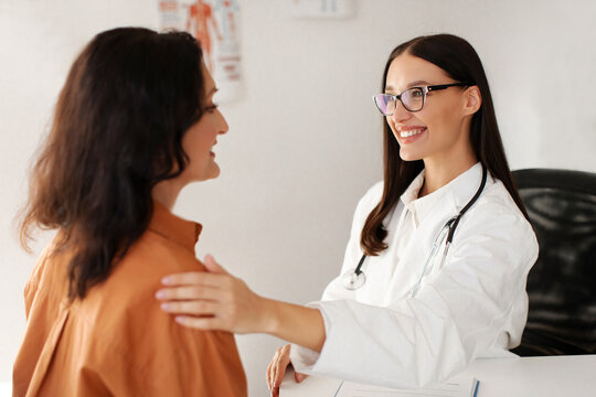 Satisfied GP doctor telling good news to middle aged female patient, congratulating on optimistic medical checkup result at appointment in office
