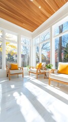 Sunlit sunroom with light wood ceiling, three beige armchairs with mustard yellow pillows, and large windows showcasing autumn foliage.  White marble flooring reflects sunlight