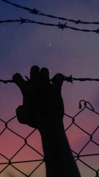 Hand silhouette at night: frantic grip on metal bars against starry sky &mdash; despair and struggle in one frame. Looping video.