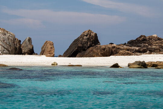 Rocky beach with striking formations and clear blue waters under a bright sky. A peaceful and secluded coastal spot ideal for relaxation and appreciating nature's beauty.