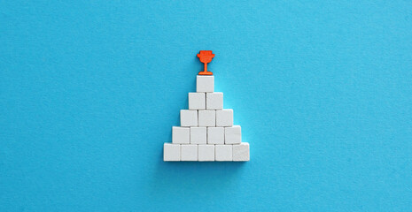 Pyramid with a trophy on top. Achieving success.